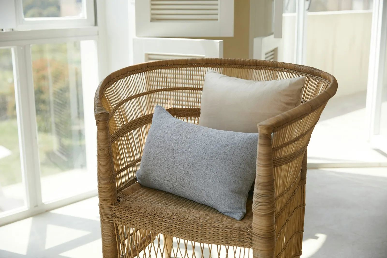 A rattan chair with soft cushions in a bright, quiet room