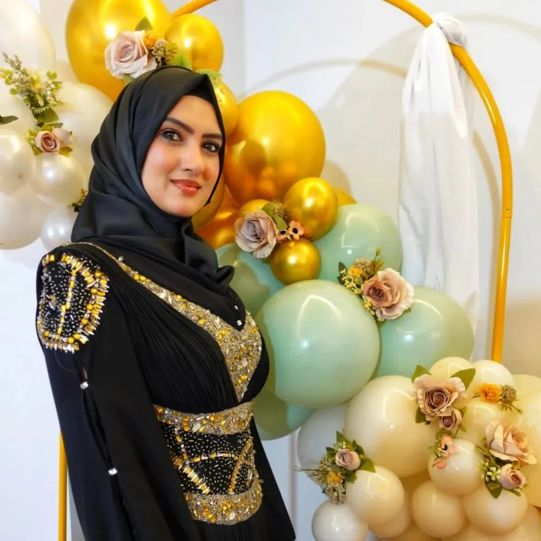 Razia Rangrage smiling at a celebration, beside gold and blush balloons