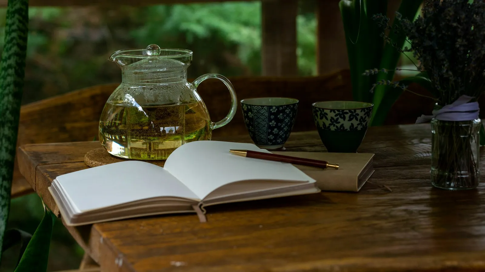 A teapot, two cups and an open notebook on a wooden table